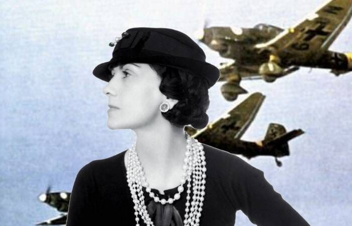 Coco Chanel ikonikus fekete-fehér kosztümben, gyöngyékszerekkel és klasszikus kalappal – a modern elegancia születése.